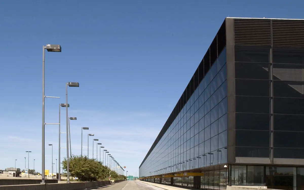 The long glass-and-steel passenger terminal at Mirabel Airport beside an empty access road