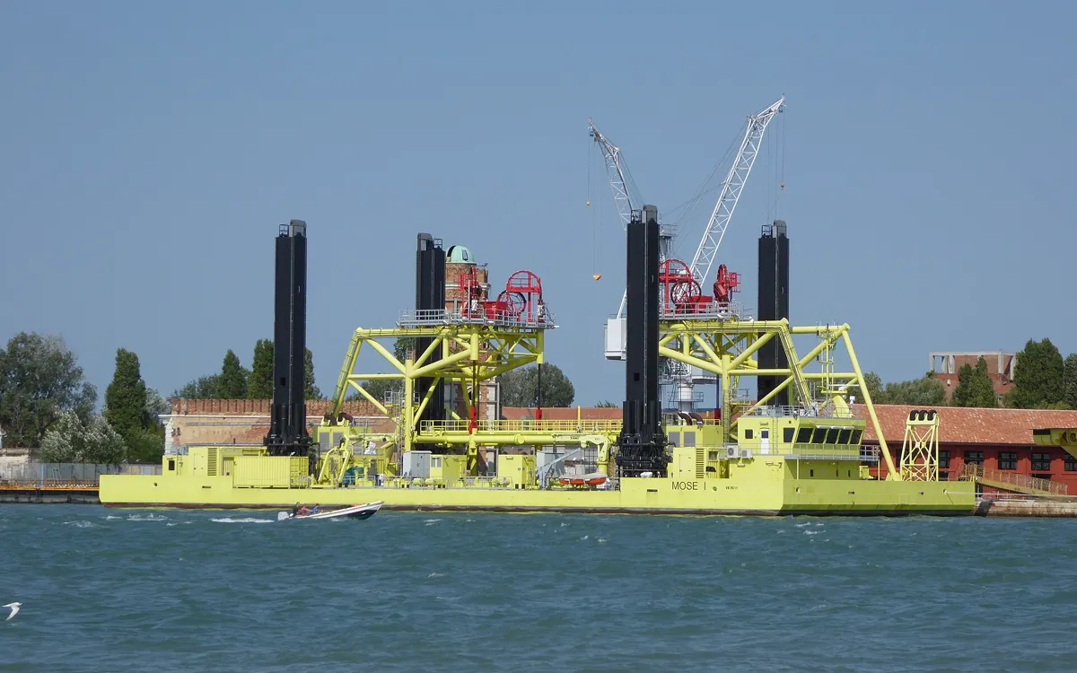 A yellow jack-up construction barge with cranes working on the MOSE barrier in the Venice lagoon