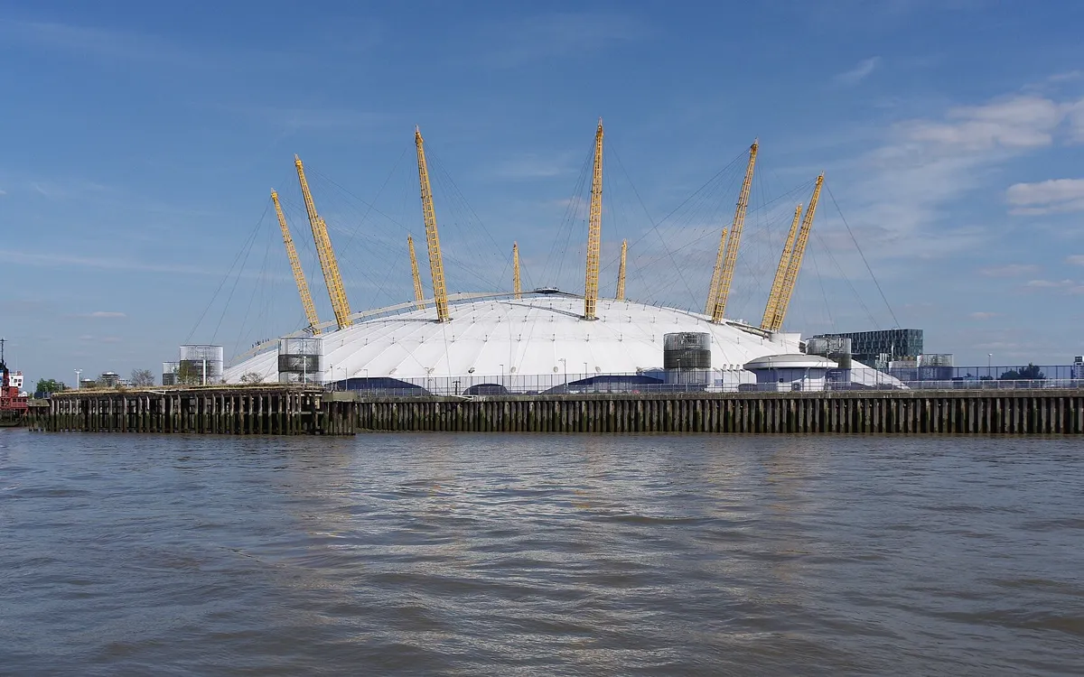 The white tent roof and yellow support masts of the Millennium Dome seen across the River Thames
